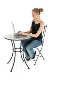 Image of person sitting at a table on their computer.